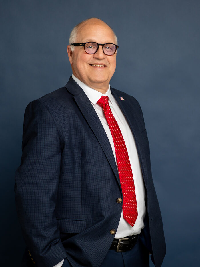 Steve Shoffner, Erie County Commissioner since 2019, standing in a dark suit and red tie