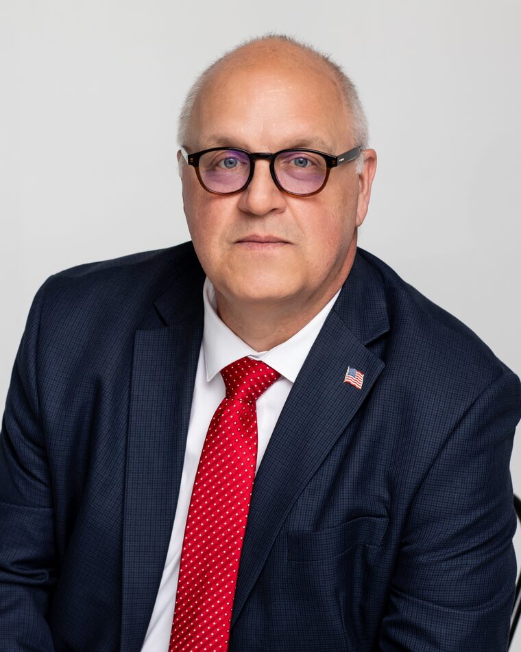 Steve Shoffner, candidate for Erie County Commissioner, seated in a dark suit and red tie